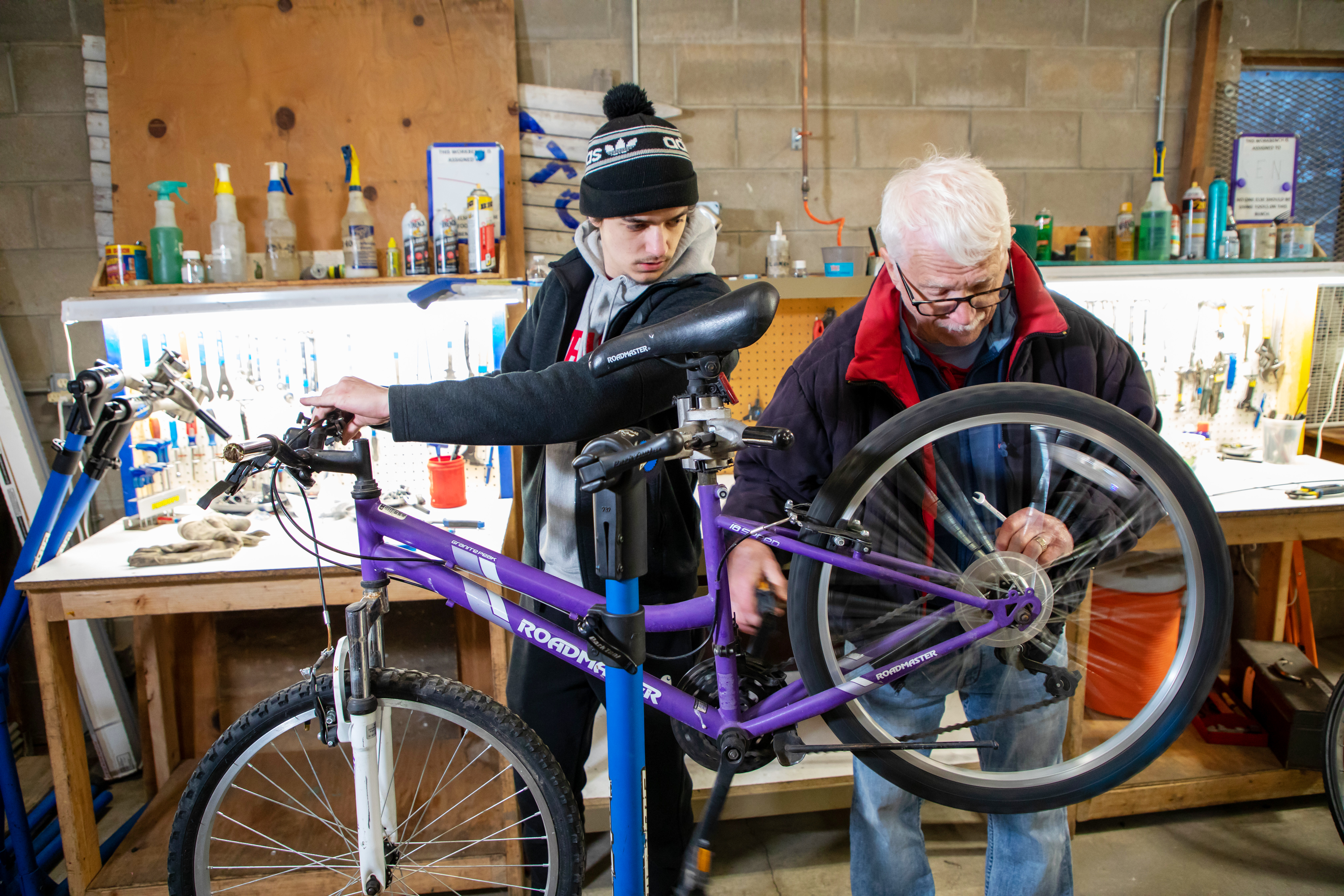 Two people working on bicycle.