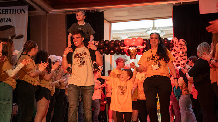 Luke Woosley carries a Miracle Kid on his shoulders as the family enters at HuskerThon.