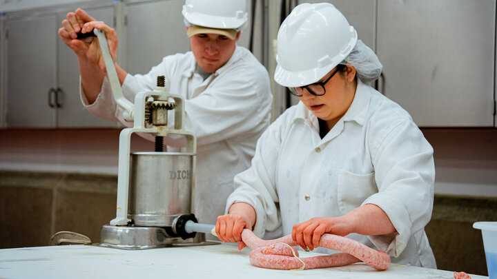 Two food scientists, a man and a woman, make sausage.