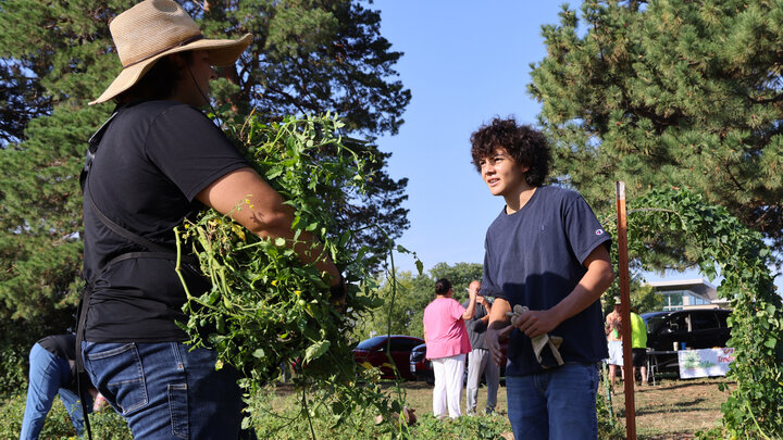 Timothy Thielen, arms full of plants, talks with a youth.