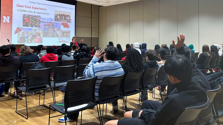 Sue Ellen Pegg, recruitment coordinator with the College of Agricultural Sciences and Natural Resources, speaks in front of at least three dozen high school students, seated in chairs. Two students have a hand raised.