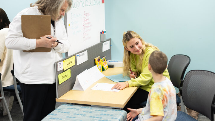 Addie Olson (center), a senior elementary education major, works with a young male student at a desk in the Kit and Dick Schmoker Reading Center on Feb. 24 as Susan Dinsdale (left), a supervisor, observes.