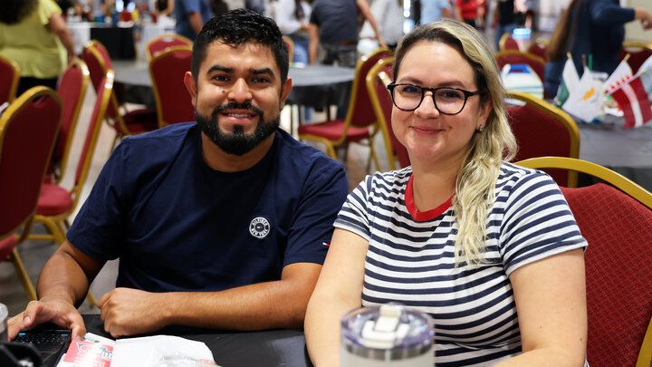 A man and woman, seated at a table, smile for a photograph during the 2024 Nebraska Small Business Conference in Lincoln.