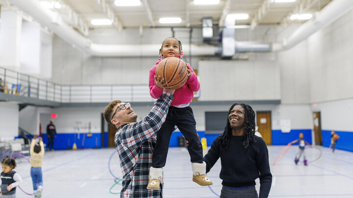 Ben Bentzinger, a senior in criminal justice, and Francisca Lawson Tettevie  a graduate student with CYAF, help Journey shoot a basket at the Malone Center.