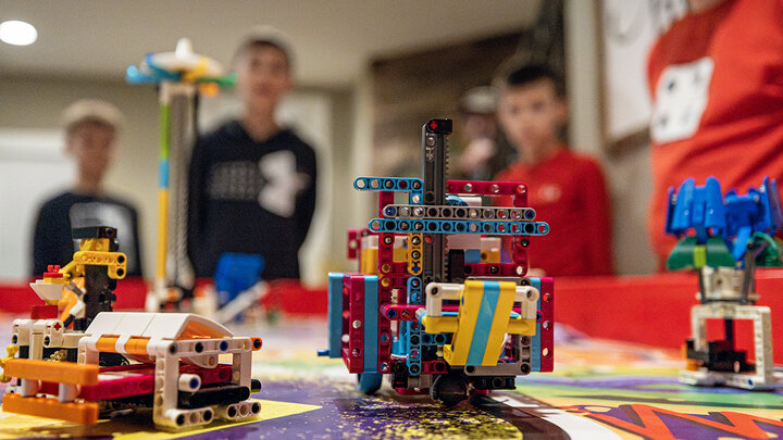 Robots made from Lego bricks sit on a FIRST LEGO League game board.