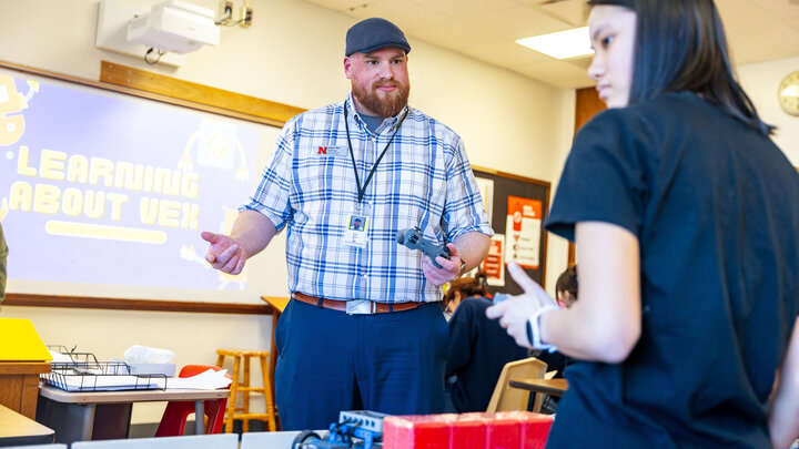 Zach Short, project director for Educational Talent Search, guides Lily Tran, a sophomore, through using the controls to make the robot move.
