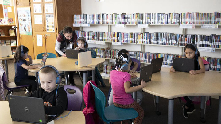 Elementary students work at laptops on coding skills