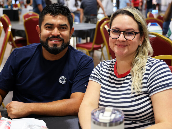 A man and woman, seated at a table, smile for a photograph during the 2024 Nebraska Small Business Conference in Lincoln.