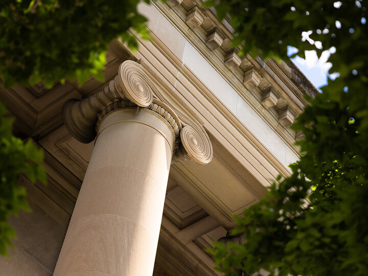 Detail of a column on the south side of Pound Hall, surrounded by the greenery of trees.